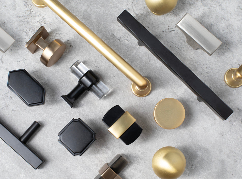 Collection of various cabinet pulls and knobs on a gray surface