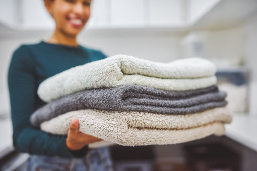 Smiling woman holding 3 folded towels