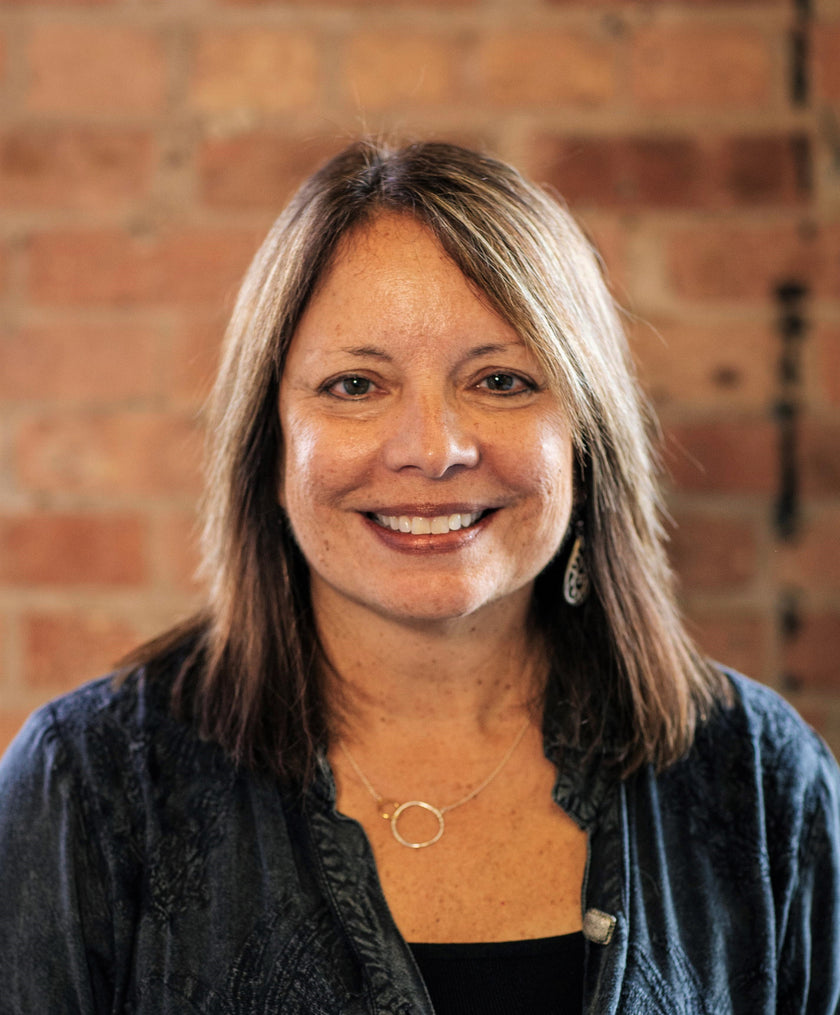 Woman smiling in front of a brick wall