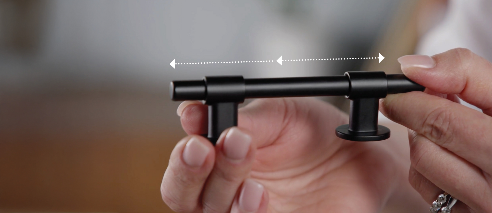 Black metal handle held by hands with a blurred background