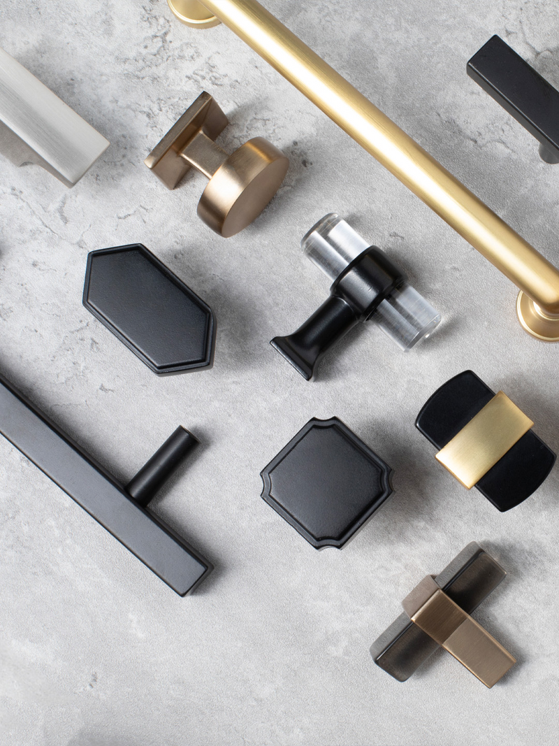 Collection of various cabinet handles and knobs on a gray surface