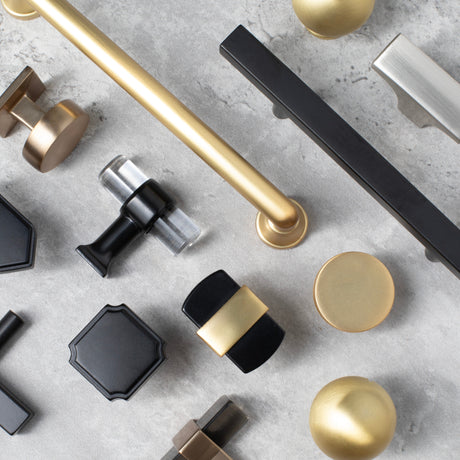 Collection of various cabinet pulls and knobs on a gray surface