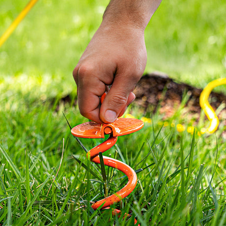 Hand using a lawn anchor tool in grass