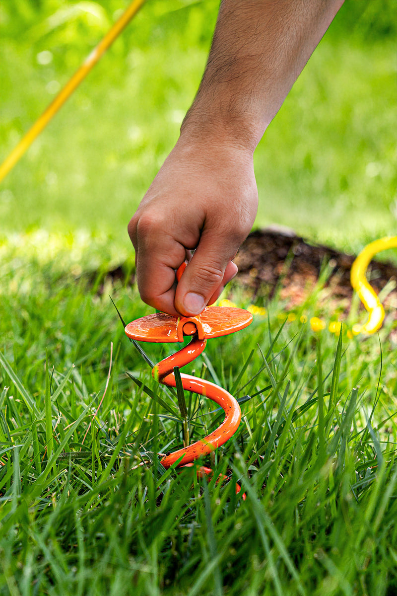 Hand using a lawn anchor tool in grass